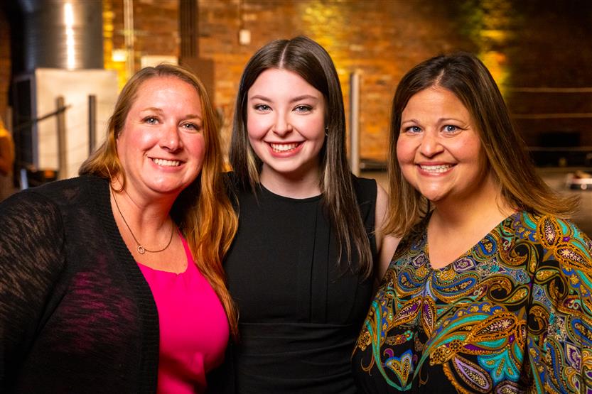 A group of three women smiles